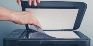 Joes Printer Buying Guide Home Image Hand Placing page on flat bed scanner